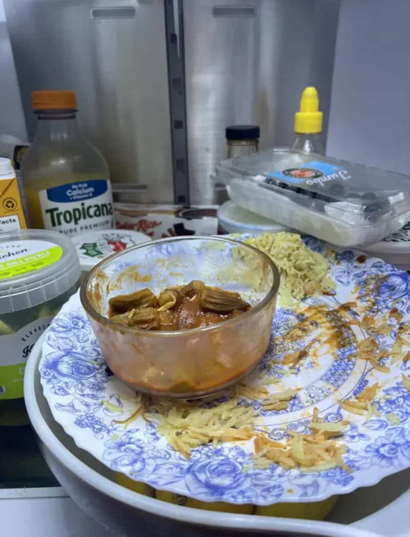 Empty plate with some food remnants, bowl of sauce, and condiments in the fridge.