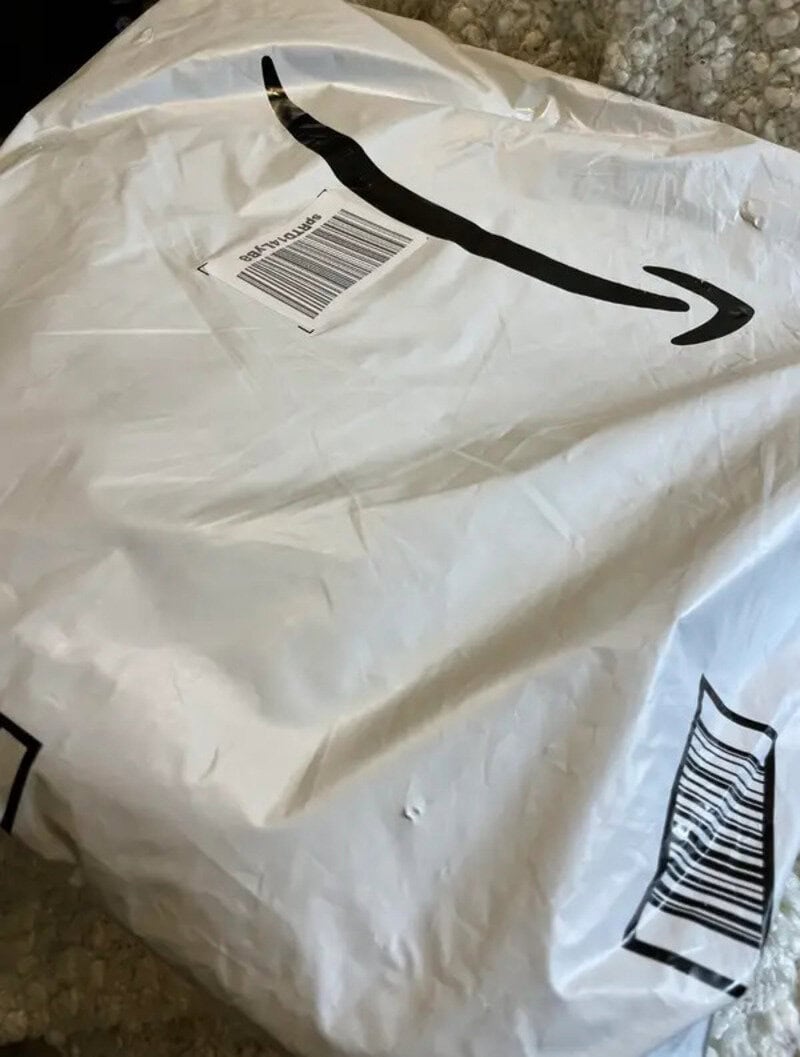 Amazon package in a crumpled white plastic bag with barcode and arrow logo.
