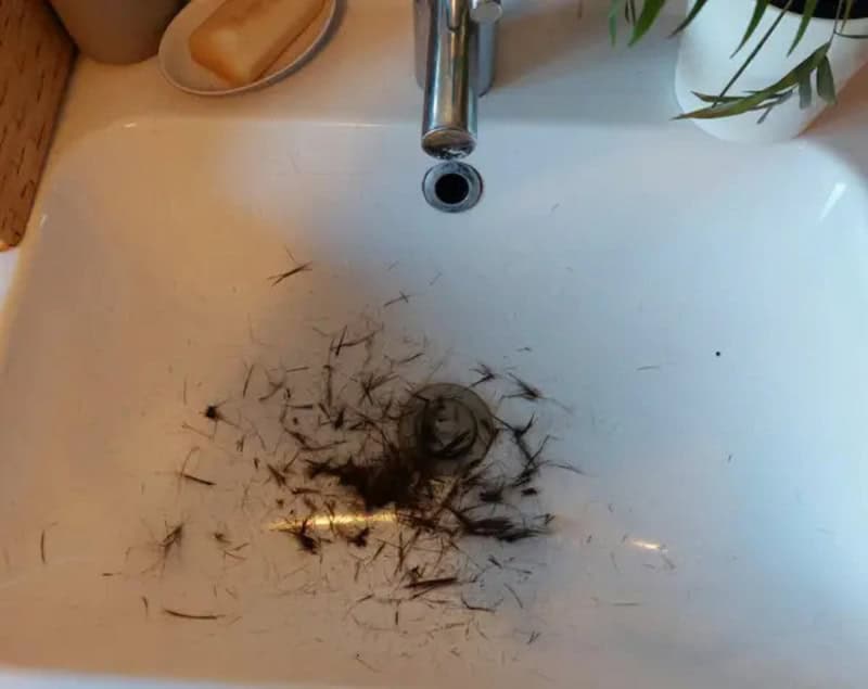 Dirty sink with hair and debris around drain and faucet.