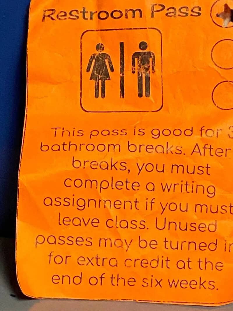 Restroom Pass with male and female icons, orange background, worn and crumpled.