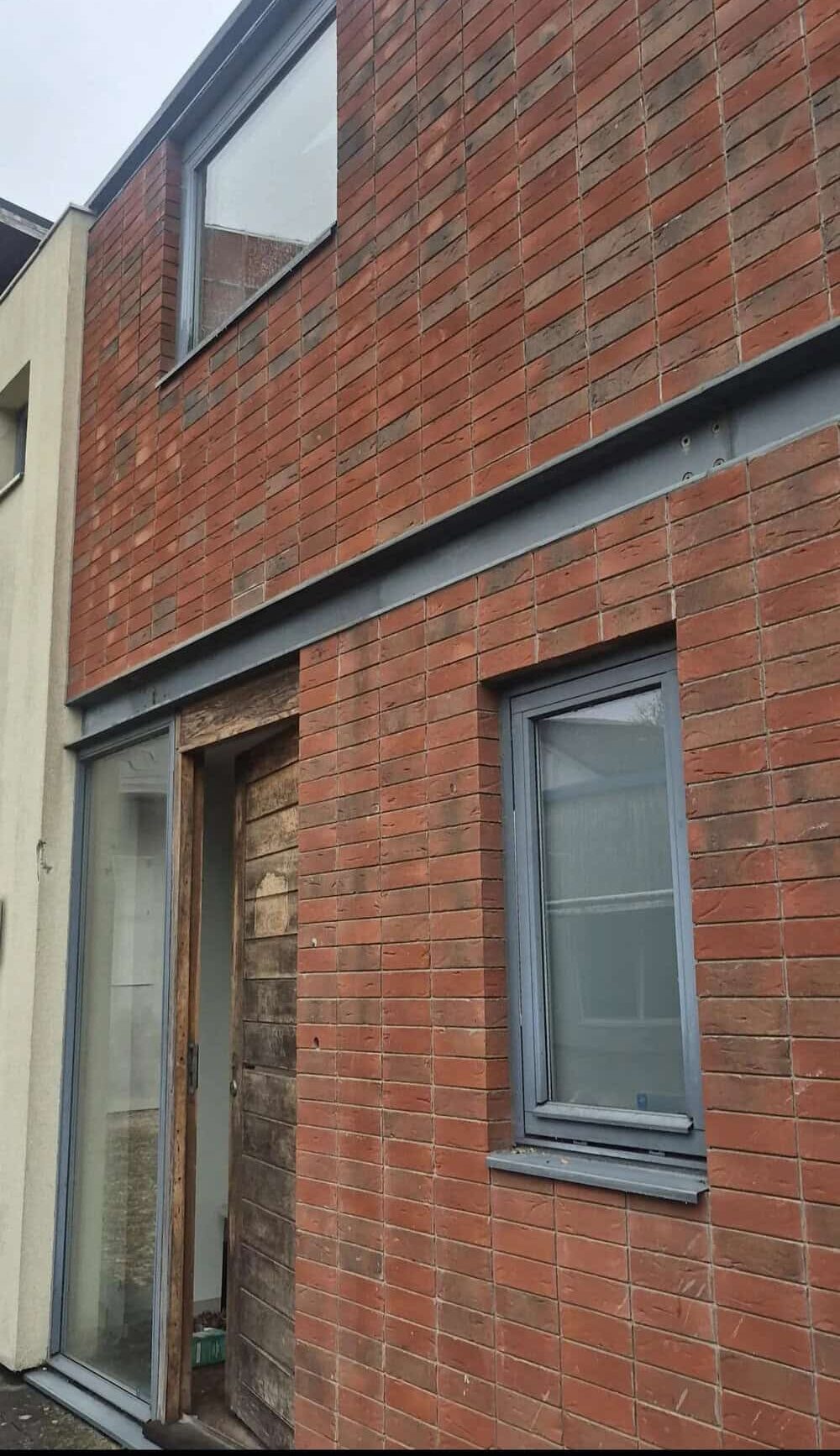 Close-up of a brick building with a window and a door under construction.