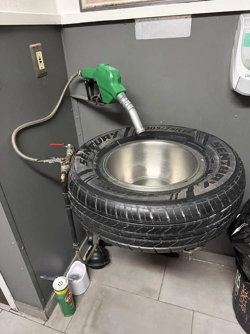 Tire sink with a faucet and hose in a gray room, labeled 'mildly interesting'.