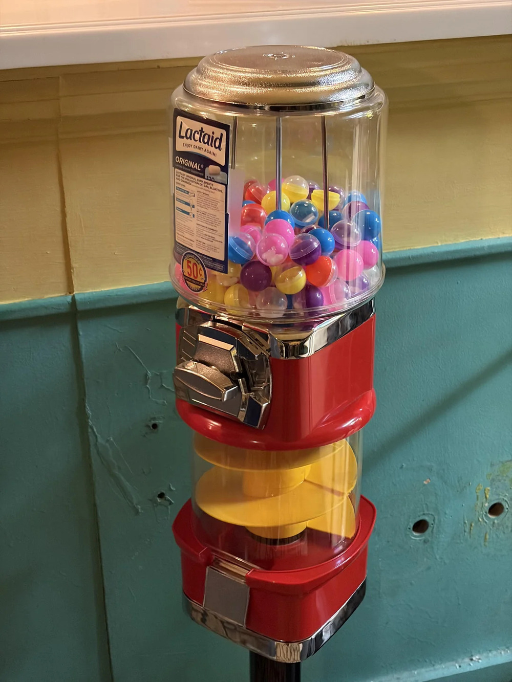 Gumball machine with colorful gumballs and a Lactaid milk carton on top.