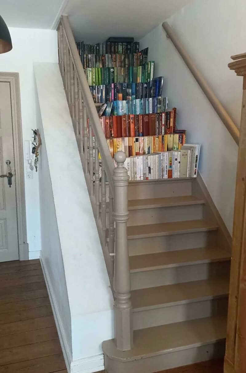 Books arranged on stairs in a house, forming a colorful display.