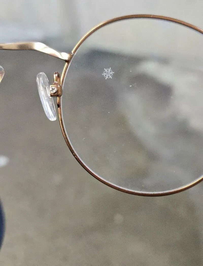 Close-up of eyeglasses with a tiny snowflake on the lens.