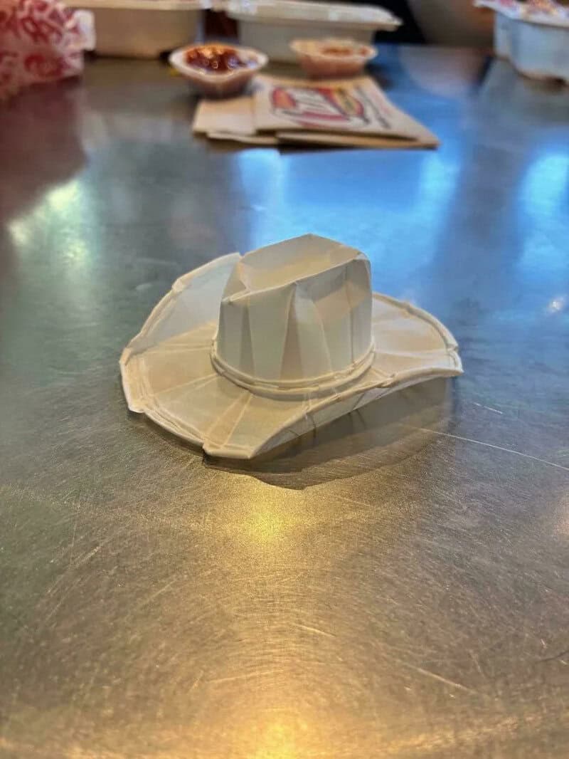 Paper cowboy hat on a metallic table with blurred background.