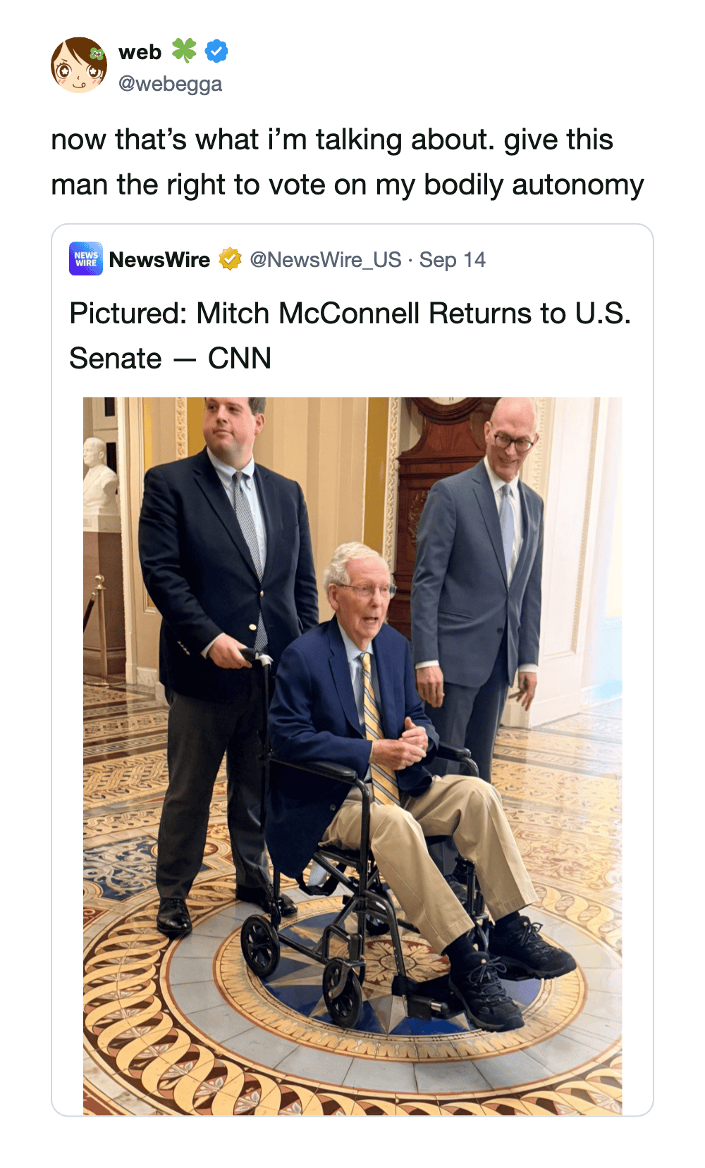 Mitch McConnell in a wheelchair with two men standing beside him in a formal setting.