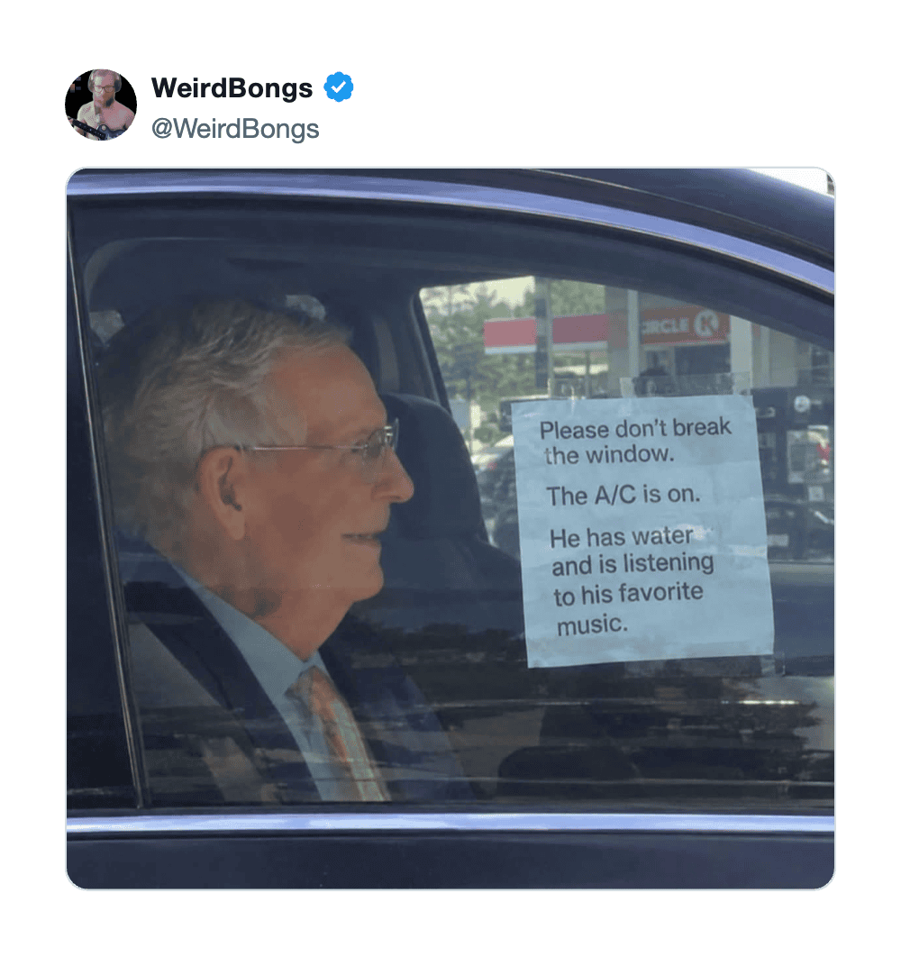 Man in car with a note on the window about the A/C and music.