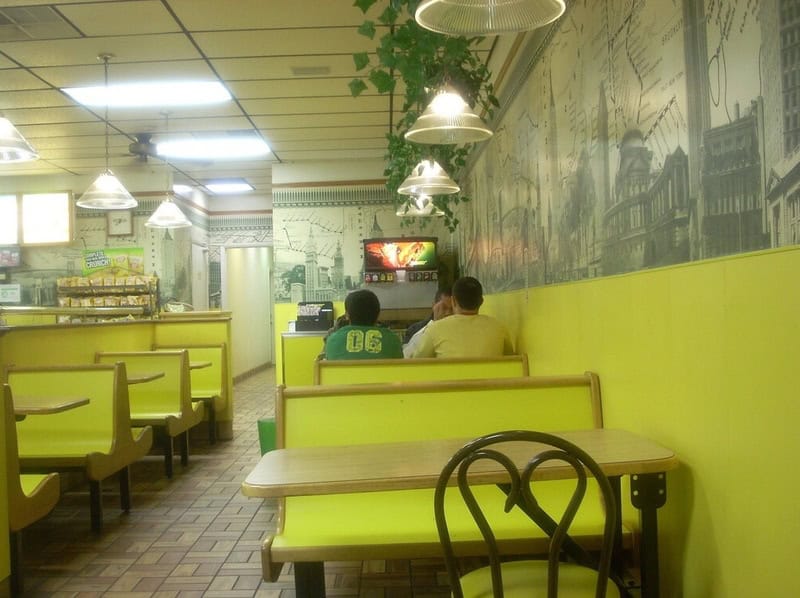 Interior of a retro fast-food restaurant with yellow booths and wall murals.
