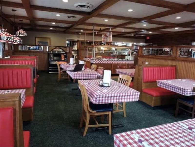 Empty fast-food restaurant with red booths and checkered tablecloths.