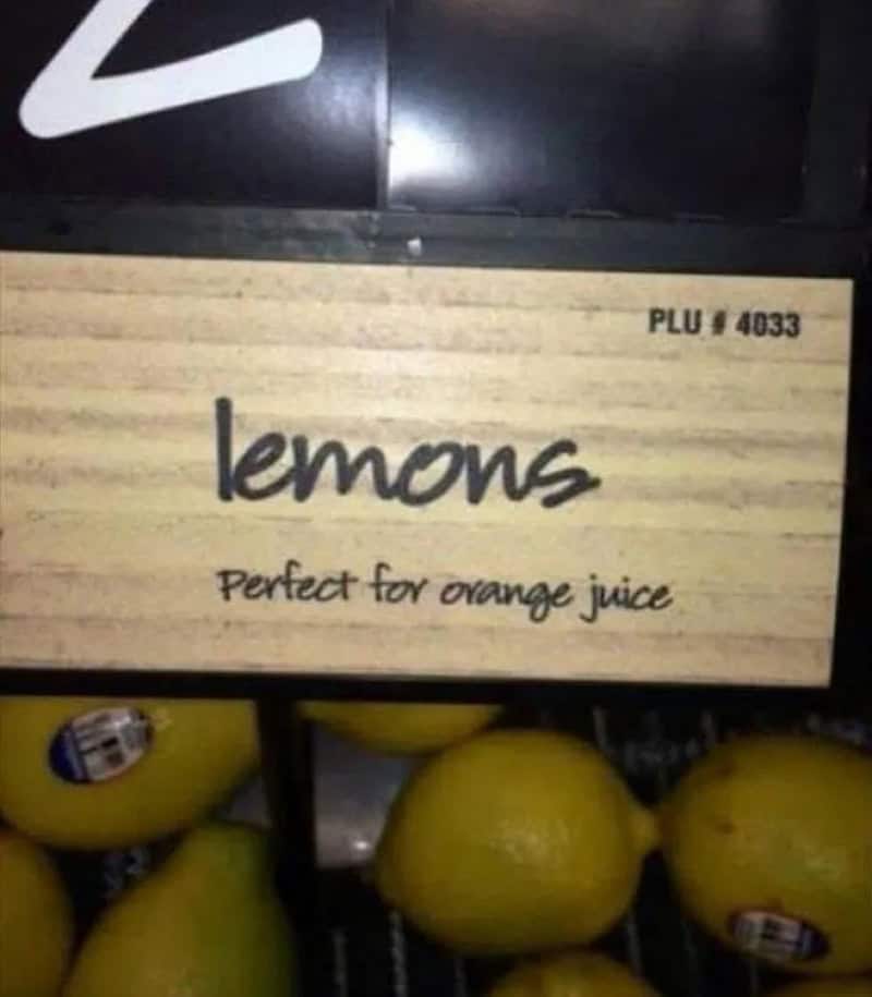 Lemons with a sign that says 'lemons, perfect for orange juice'.