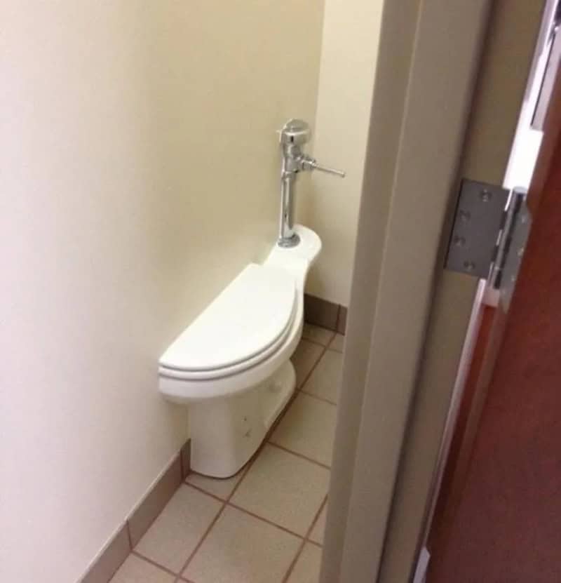 Toilet with a sink on top, in a small bathroom, next to a door.