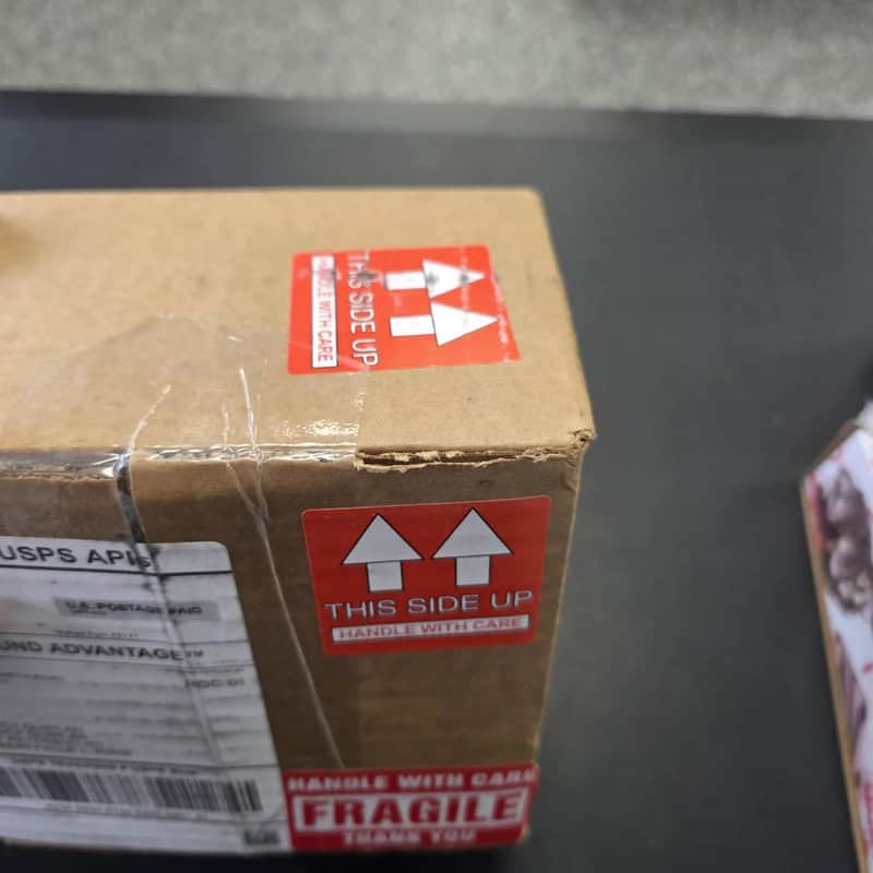 Cardboard box with red and white 'This Side Up' and 'Fragile' labels.