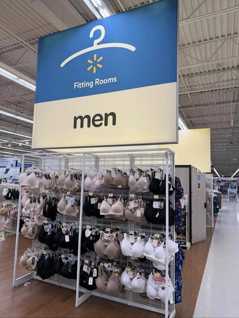 Fitting Rooms sign for men in a retail store with bras displayed below.