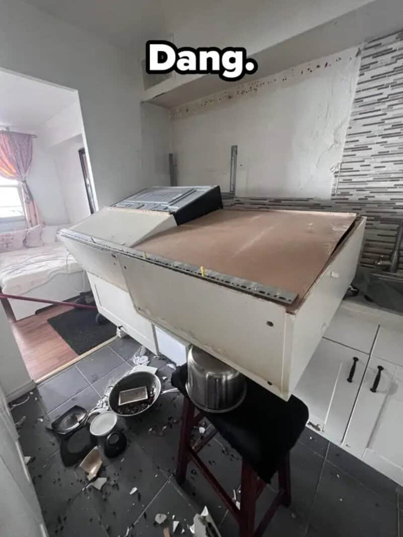 Washing machine toppled over with broken dishes on the floor.