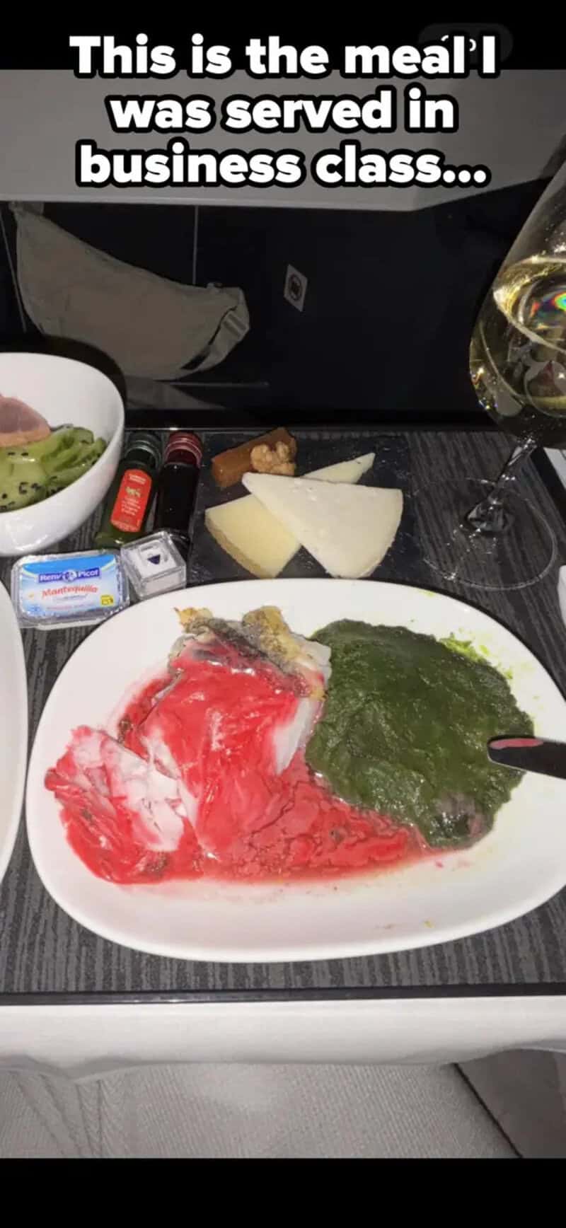 Meal served in business class with raw meat and green sauce on a plate.