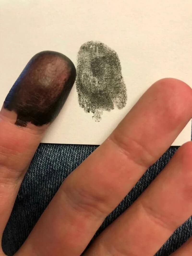 Fingertip with a fingerprint and a fingerprint smudge on paper.