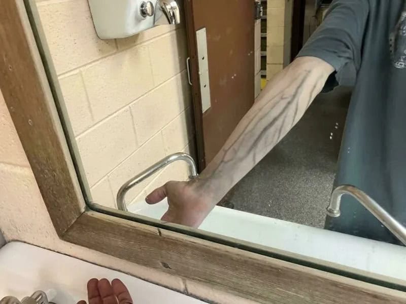 Arm with prominent veins seen in a mirror reflection.