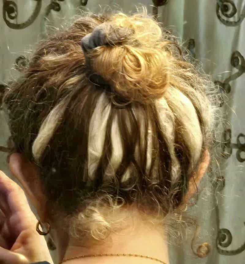 Person with unique hair featuring blonde dreadlocks and a bun on top.