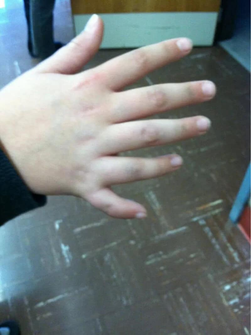 Hand with six fingers, unusual body feature, on a wooden floor.