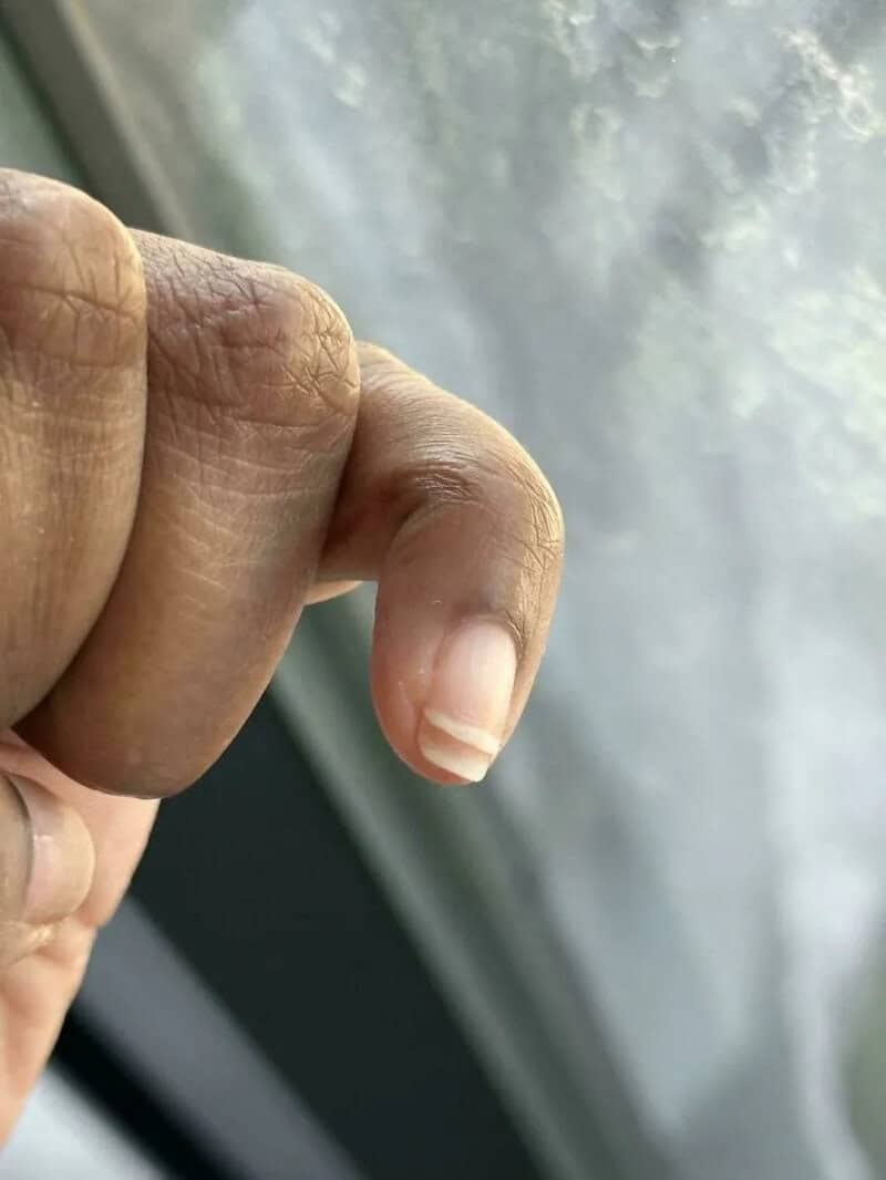 Close-up of a finger with a long, curved nail.