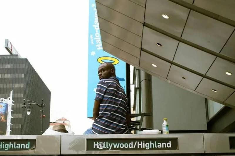 Man with a halo sticker on his head sitting on a ledge in Hollywood Highland.