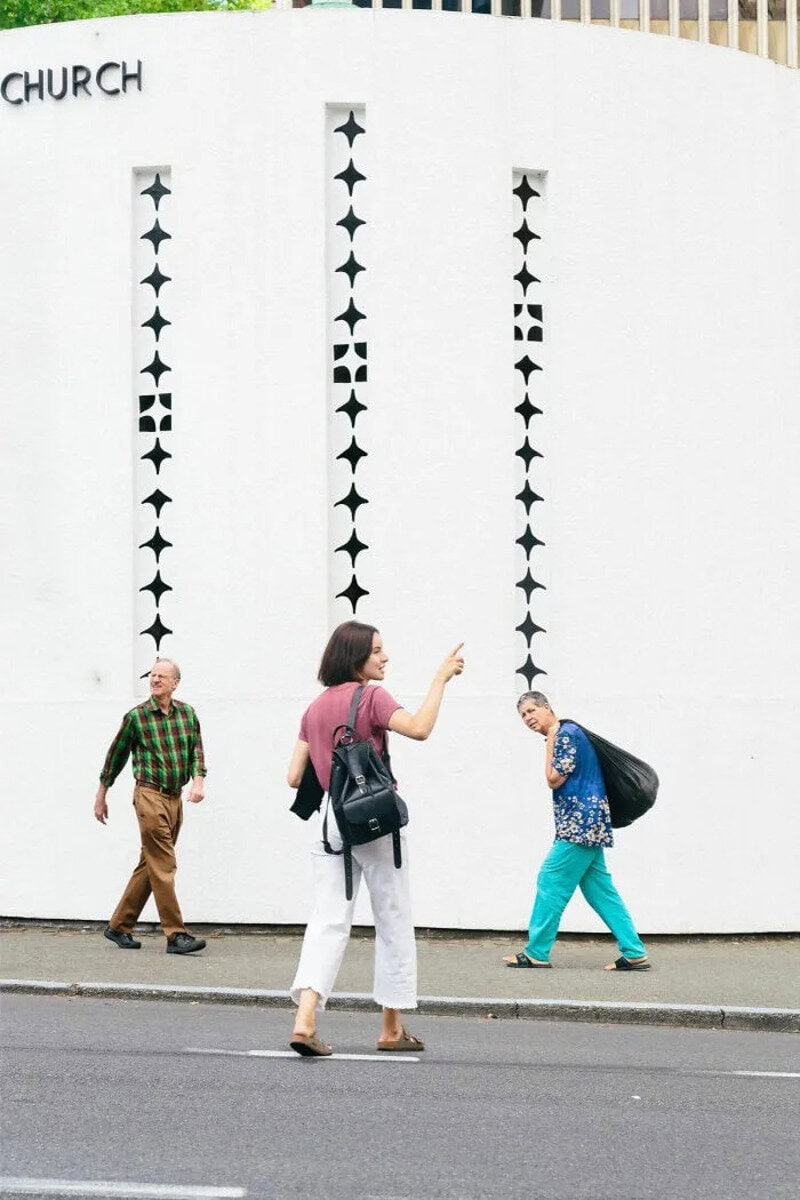 People walking past a white wall with star-shaped cutouts in Los Angeles.