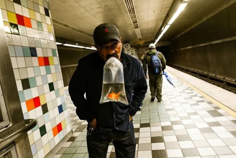 Man with a fishbowl on his face in a subway station.