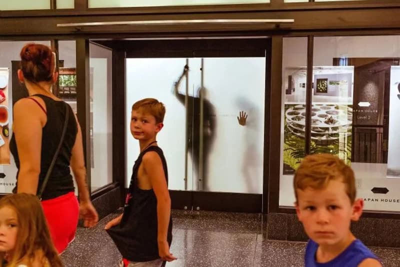 Children and a woman in a busy indoor setting with a frosted glass door.