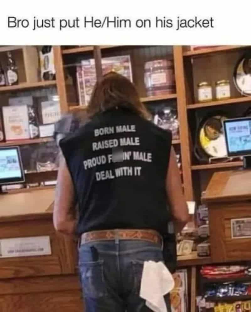 Person wearing a black vest with pronouns and phrases on the back in a store.