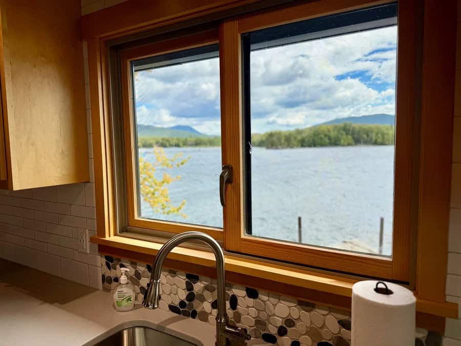 View of a lake through a window with a kitchen sink in foreground.
