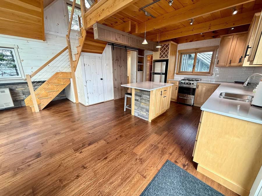 Open kitchen with wooden cabinets, island, and hardwood floors in a cabin-style home.