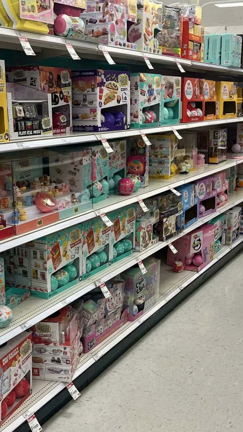 Toy aisle with various boxed toys on shelves, some in pastel colors.