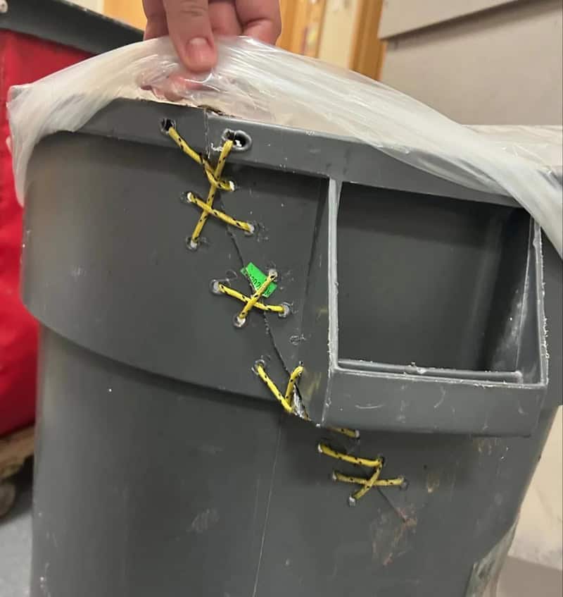 Gray plastic container with yellow zip ties and a green tag attached.
