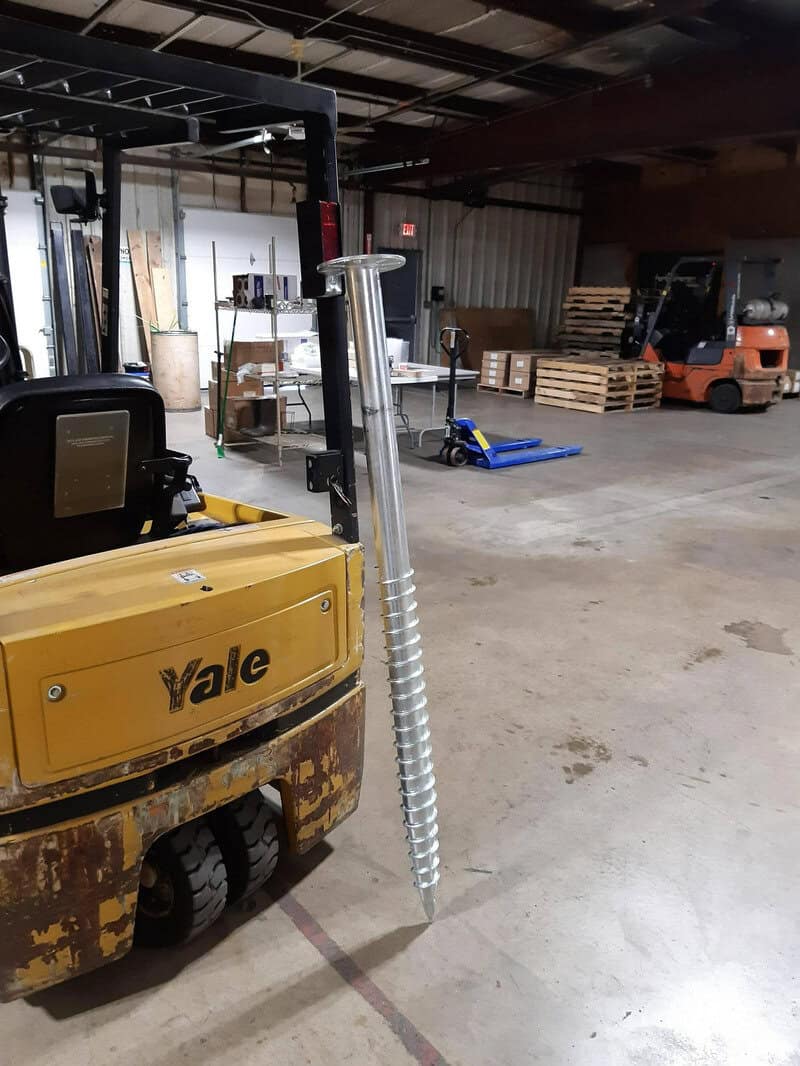 Yellow Yale forklift with a large metal spring attached to its front in a warehouse.