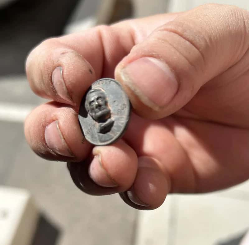 Hand holding a small coin with a face engraved on it.