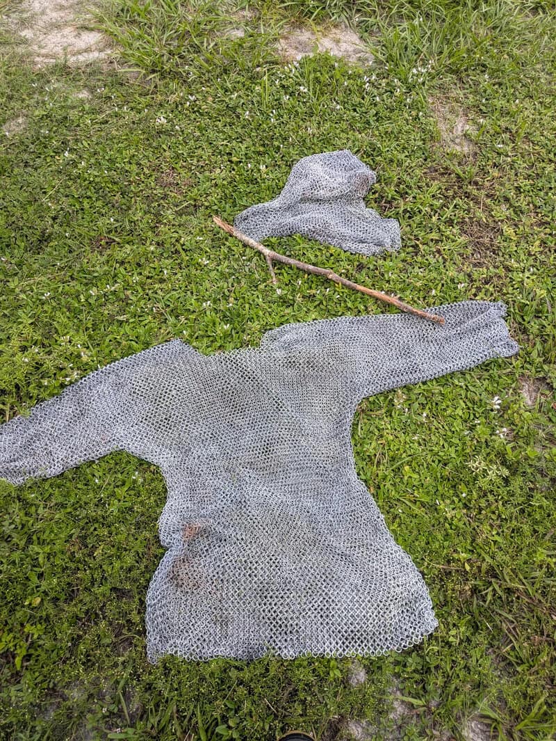 Chainmail armor, a stick, and a hat on grass, found at work.