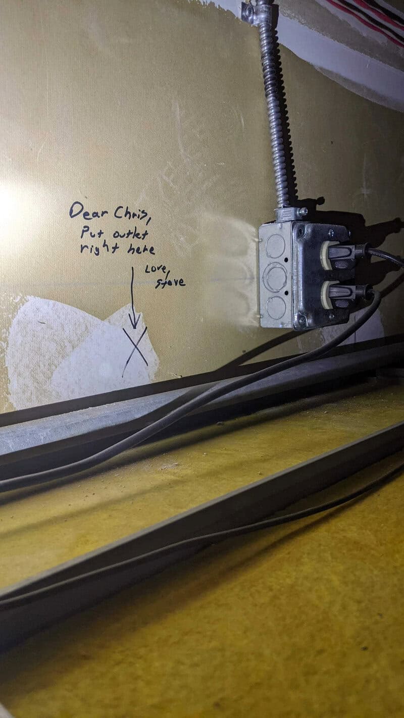 Handwritten note on wall next to electrical box: 'Dear Chizi, Put outlet right here. Love, Steve'.