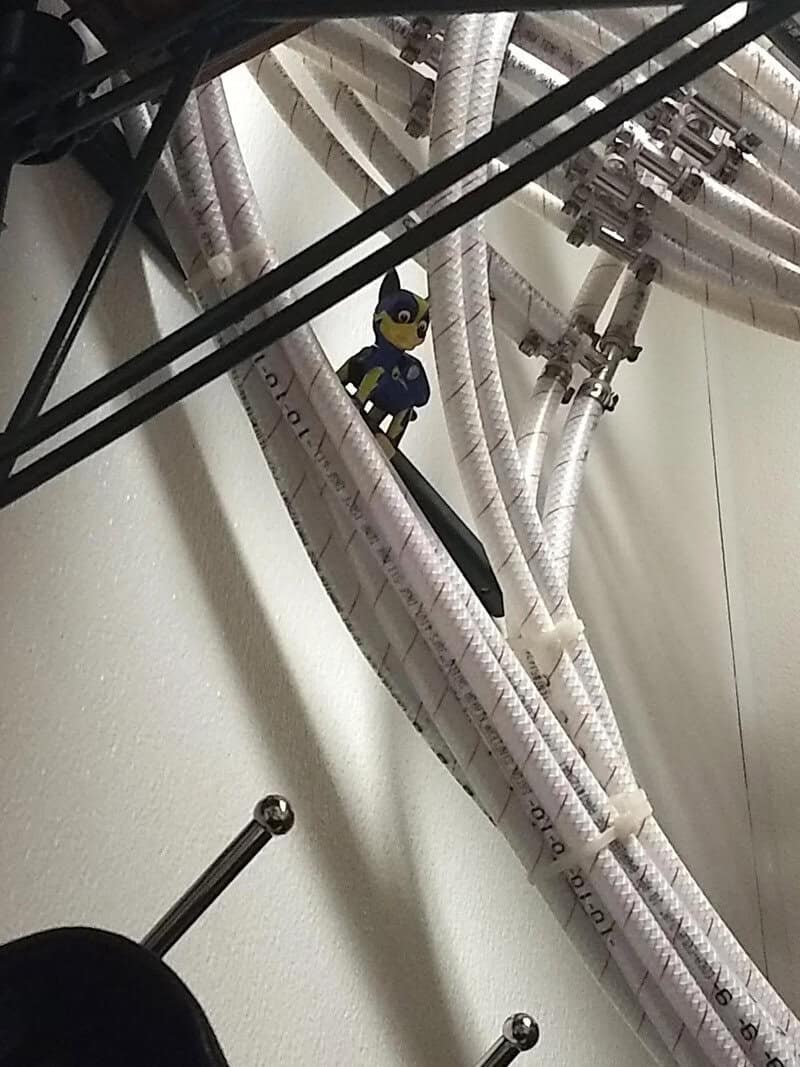 Small Batman figurine among white cables and pipes on a wall.