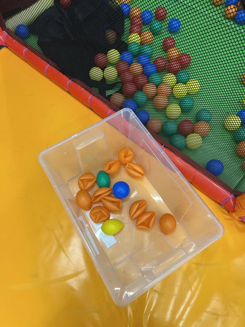 Colorful plastic balls and toys in a transparent container and ball pit.