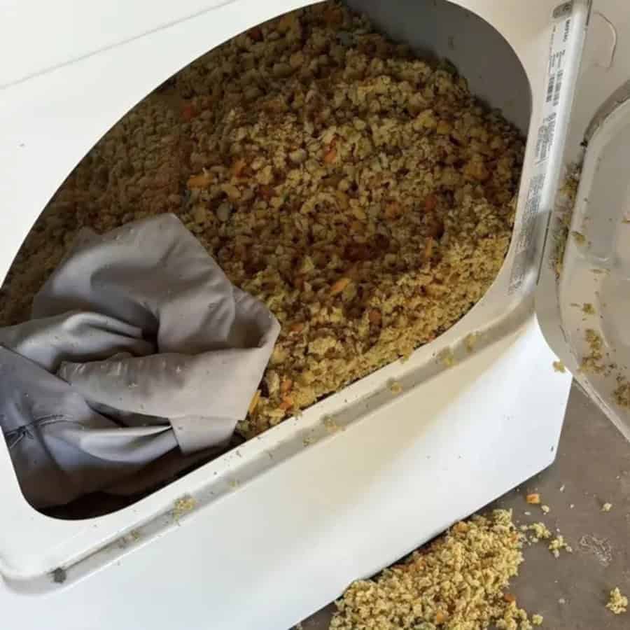 Overflowing rice cooker with spilled rice and a gray cloth inside.