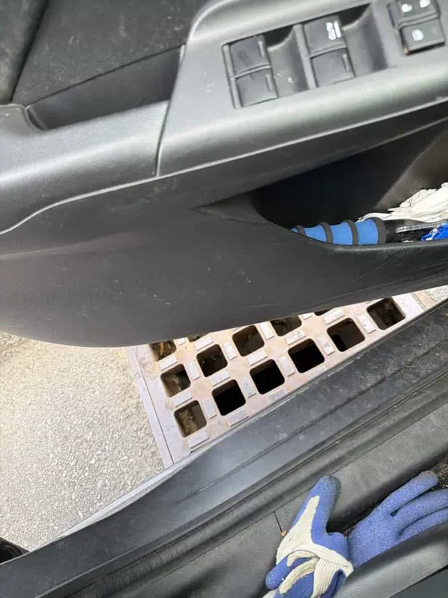 Car door interior with window controls and a glove in the footwell.