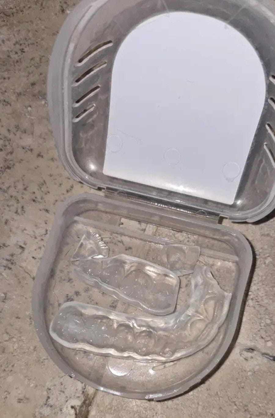 A clear plastic dental night guard inside a plastic case on a countertop.