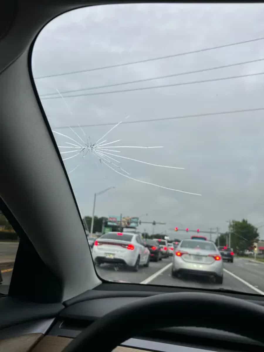Broken car windshield with multiple cracks on the passenger side.