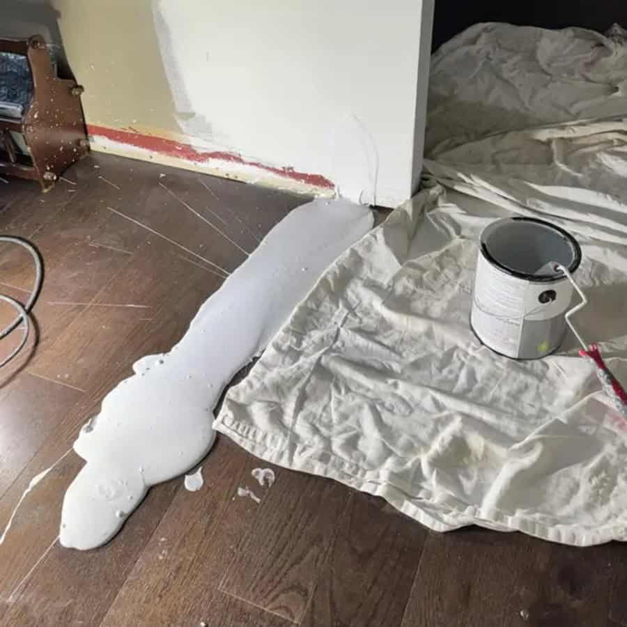 Paint spilled on the floor and a can of white paint nearby.