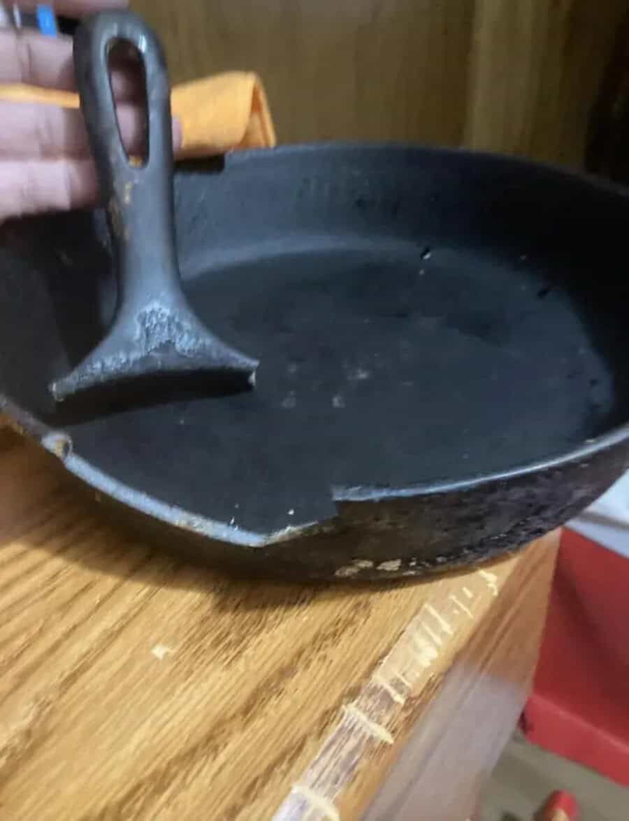 Cast iron skillet with handle resting on a wooden surface.