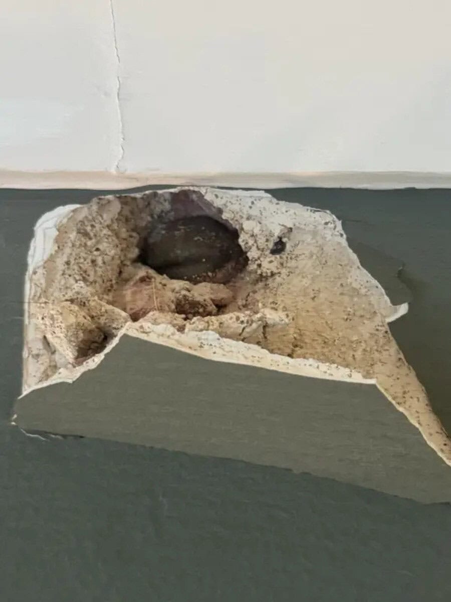Hole in the wall with exposed pipe and damaged drywall.