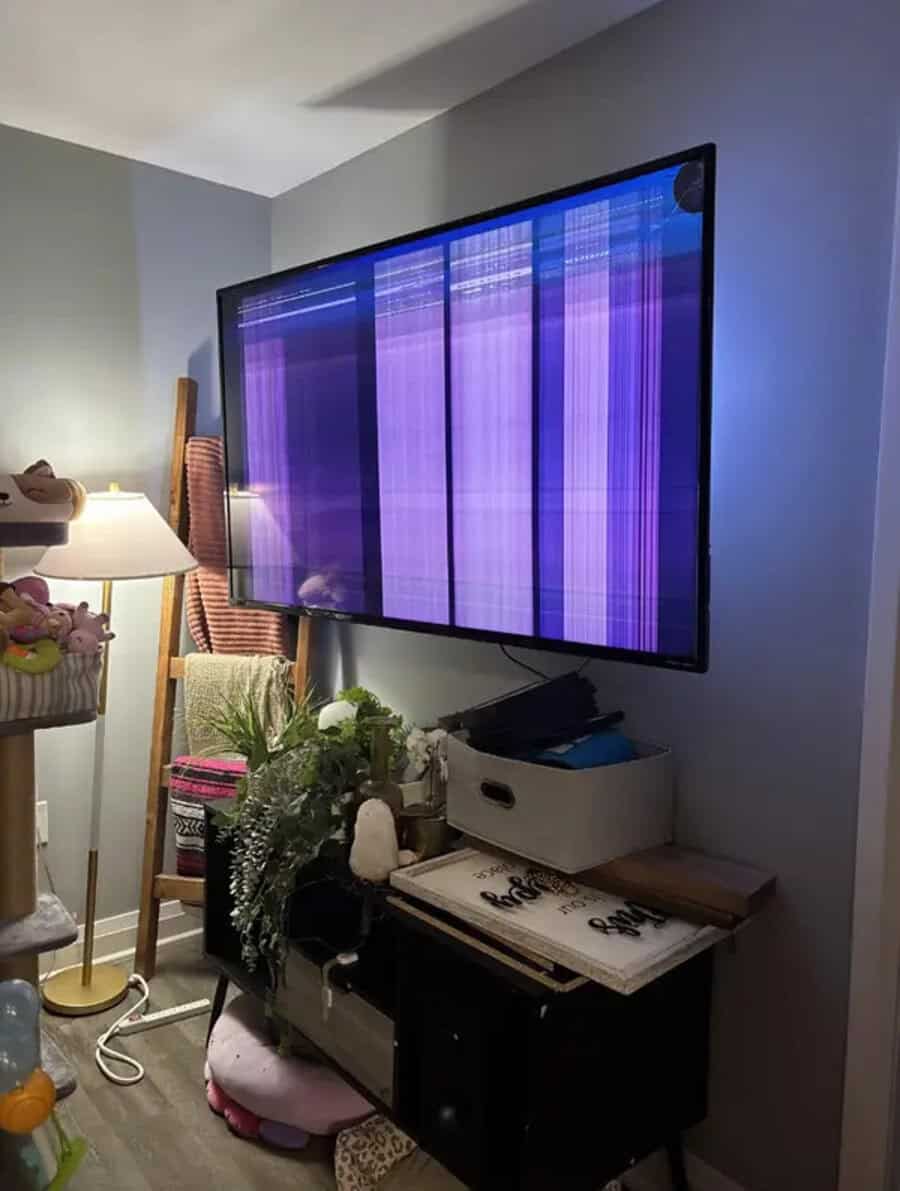 Flat-screen TV with vertical purple and blue screen lines, in a living room.