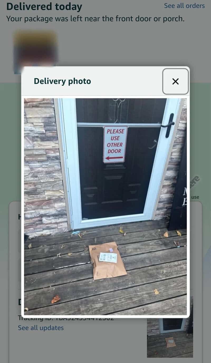 Delivery photo of a black door with a sign that says 'Please use other door' on it.