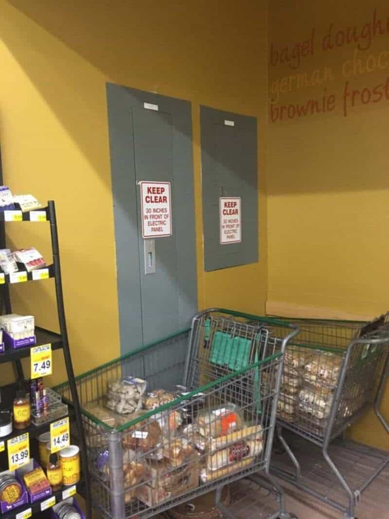 Empty shopping carts in front of a yellow wall with two gray electrical panels and a sign that says.